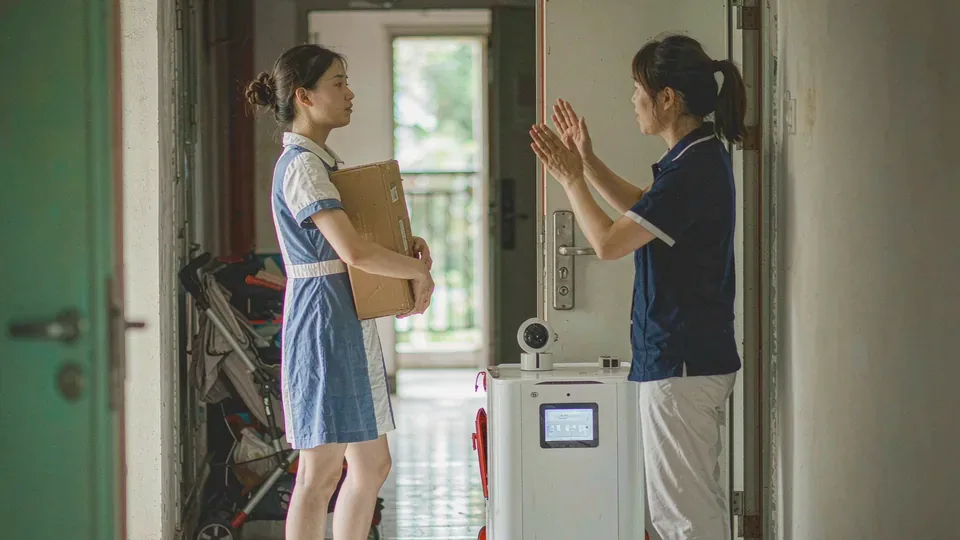 人才公寓走廊：住户抱着快递停在门口，物业管家在旁说明，一台白色配送机器人停在门口
