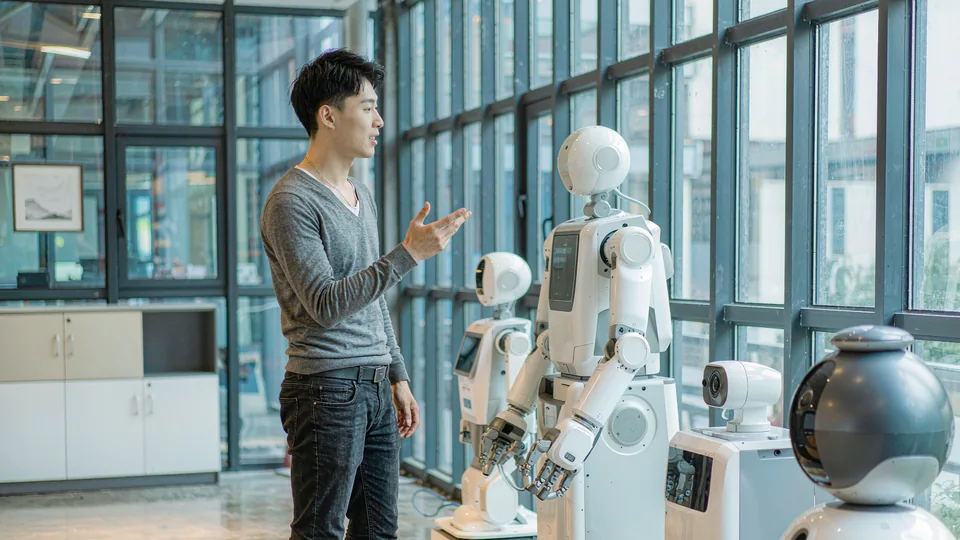 机器人展厅：工作人员蹲下与人形机器人、机器狗调试互动